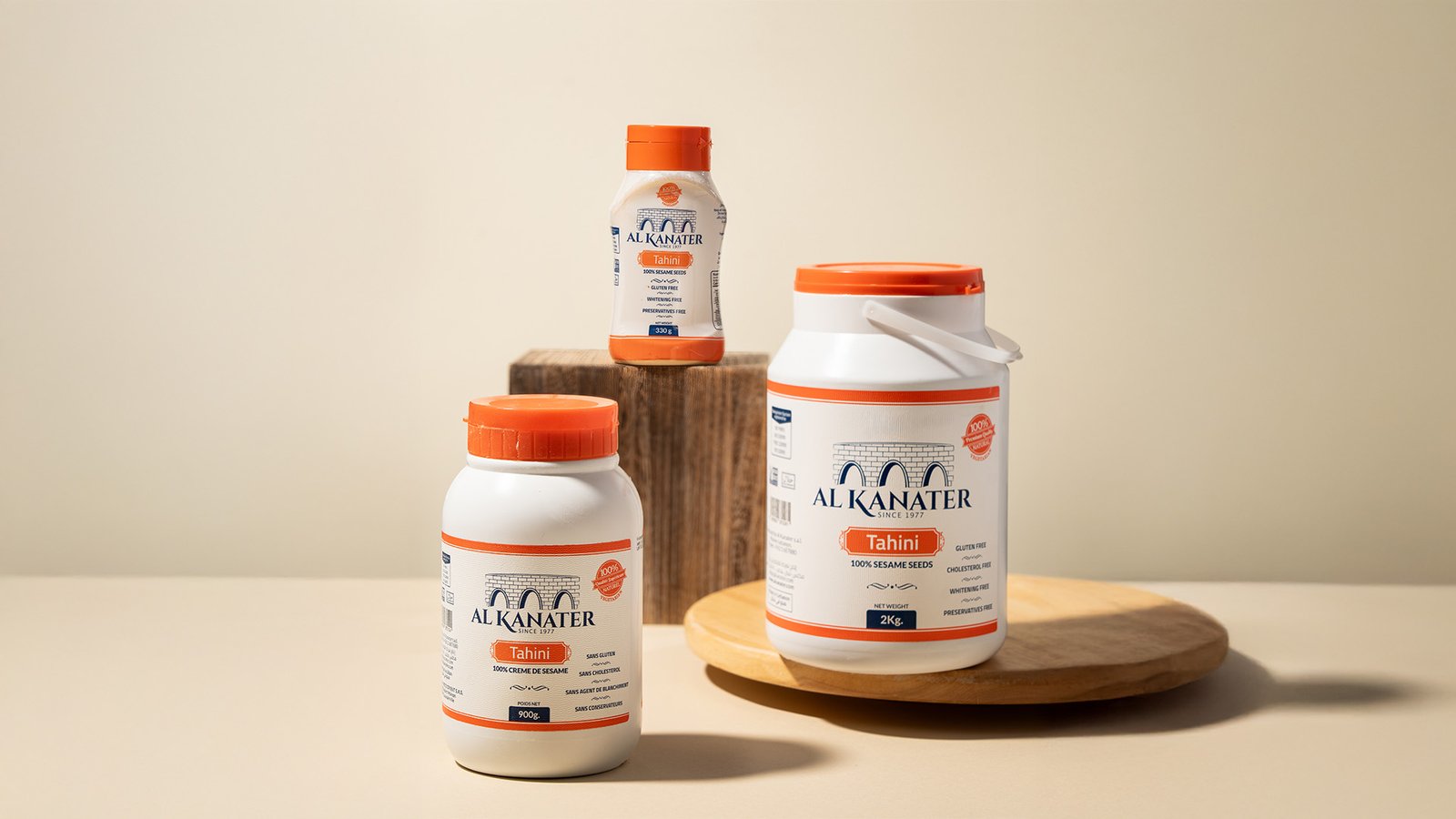 Al Kanater Tahini jars in 330g, 900g, and 2kg sizes displayed on a neutral background for food branding and marketing visuals.